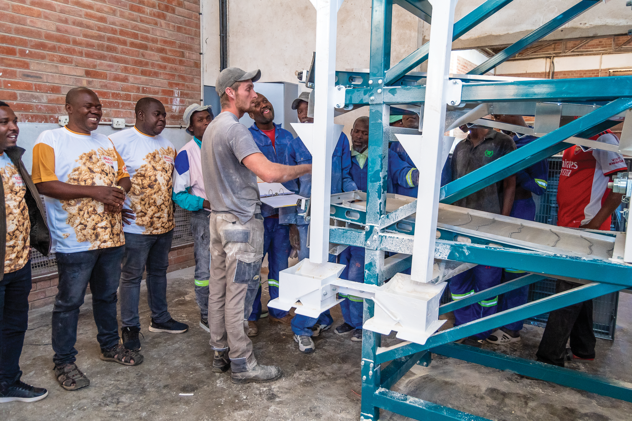 Staff and partners gathered around factory equipment during an operations walkthrough