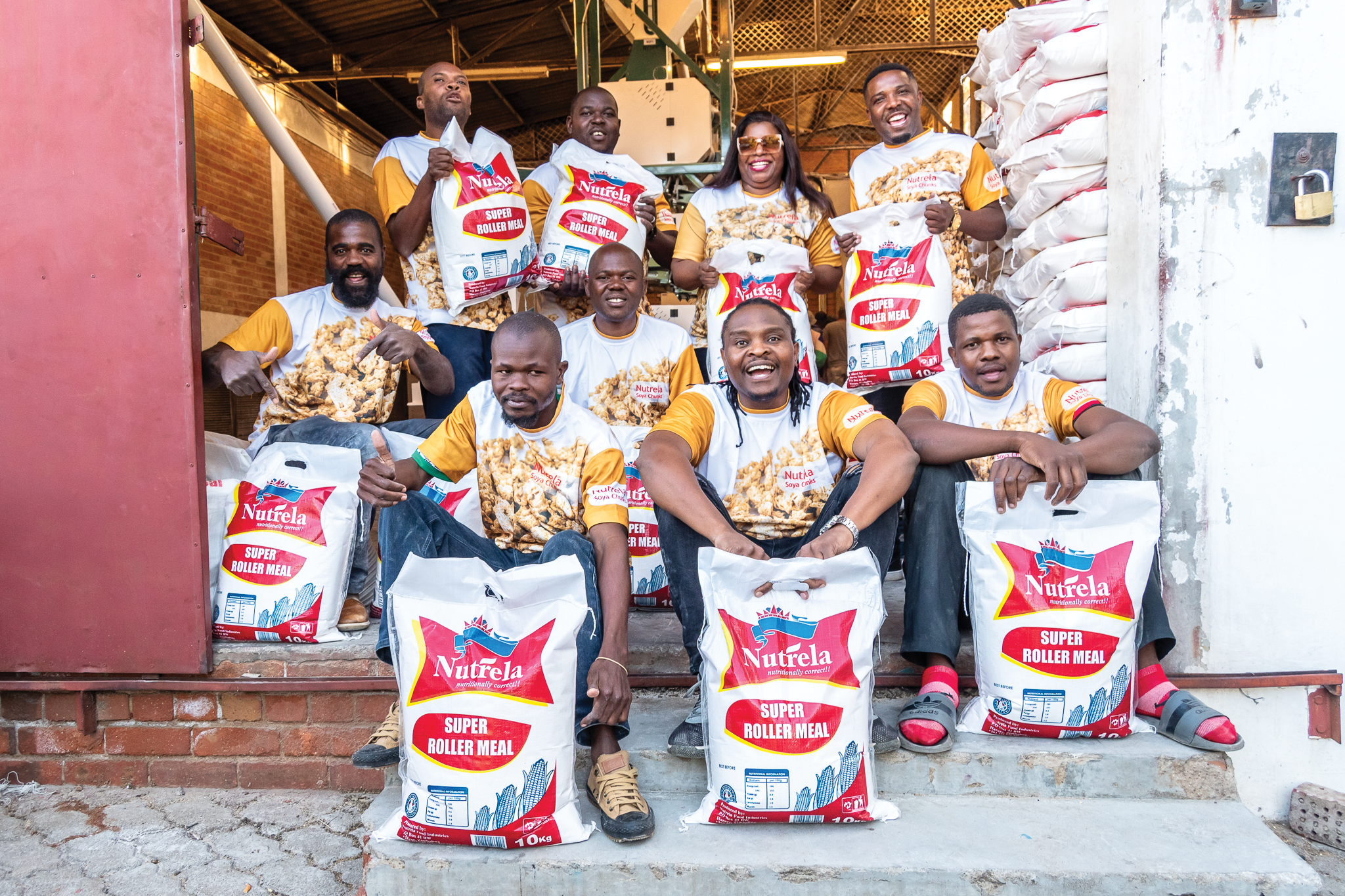 Alistar team standing with Nutrela mealie meal products at the factory entrance